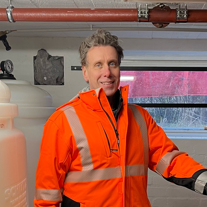 Foto von einem Mann mit einer orangefarbenen Warnjacke.